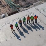 men in high vis vests and hard hats standing against the sun in a construction area